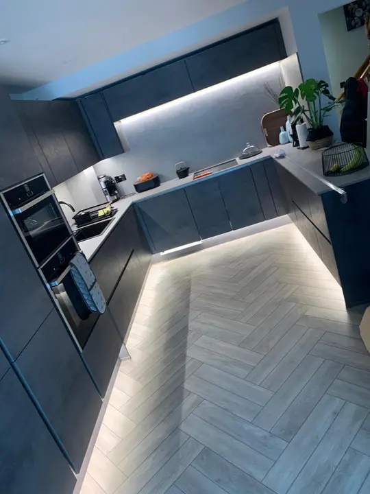 LED plinth and under-cabinet strip lighting in a modern dark kitchen