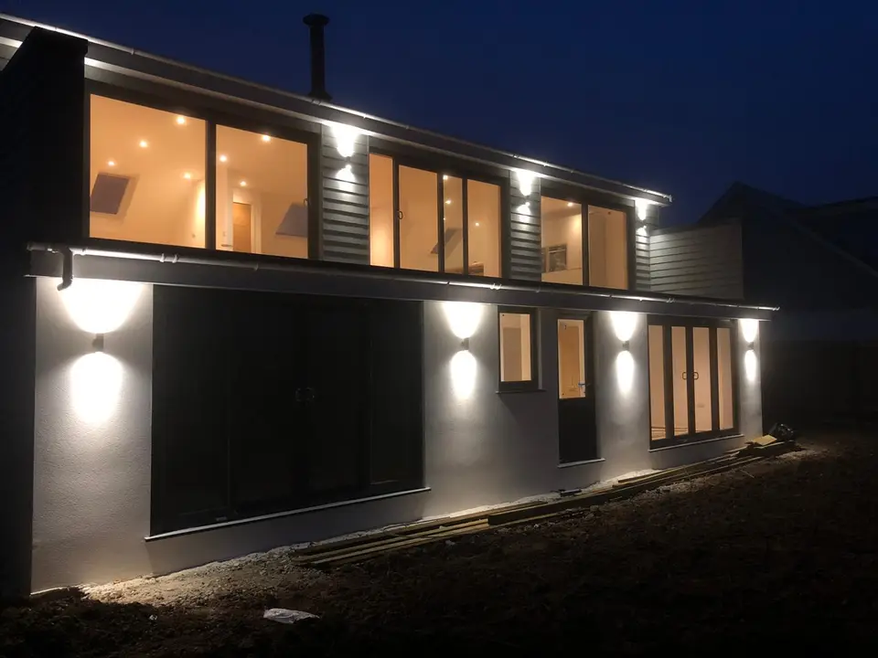 Up-and-down exterior wall lights installed across the back of a house at night