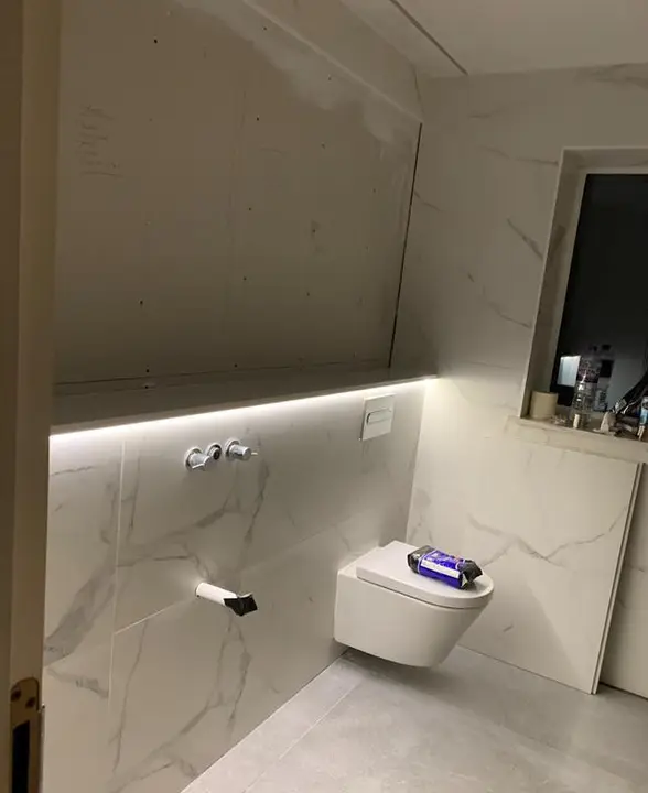 Concealed LED strip lighting in a marble-tiled cloakroom