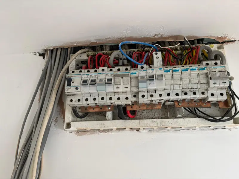 Old fuse board with exposed cabling before the upgrade